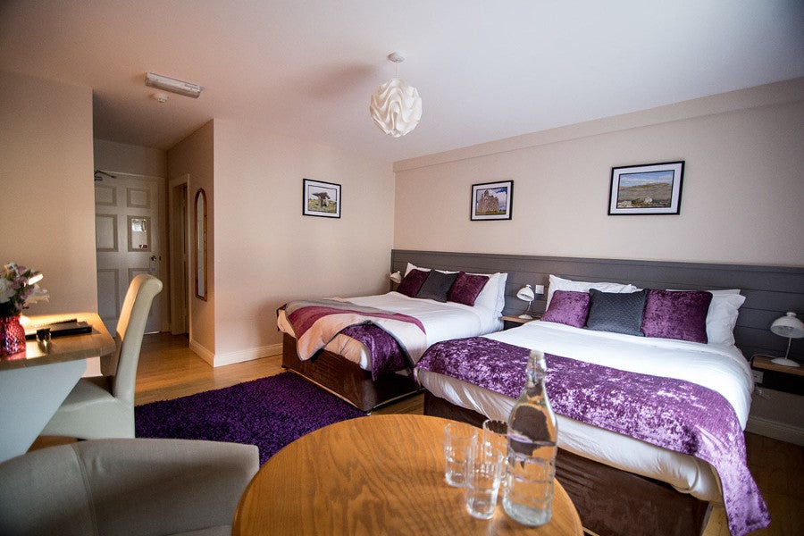 Twin bedroom with white and purple sheets