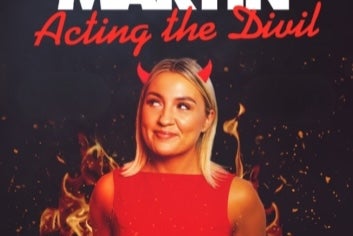 Enya Martin with new show, Acting the Divil, a smiling woman in red dress with little red horns coming out of her head