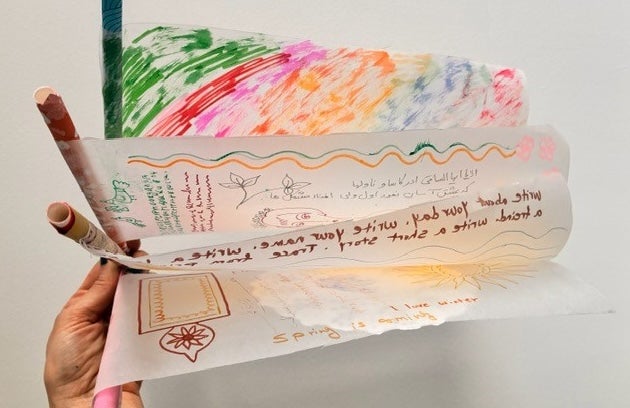 Silk Worm Families Drop-in: Ornamental Hangings - a hand holding a fan of drawings on thin white paper