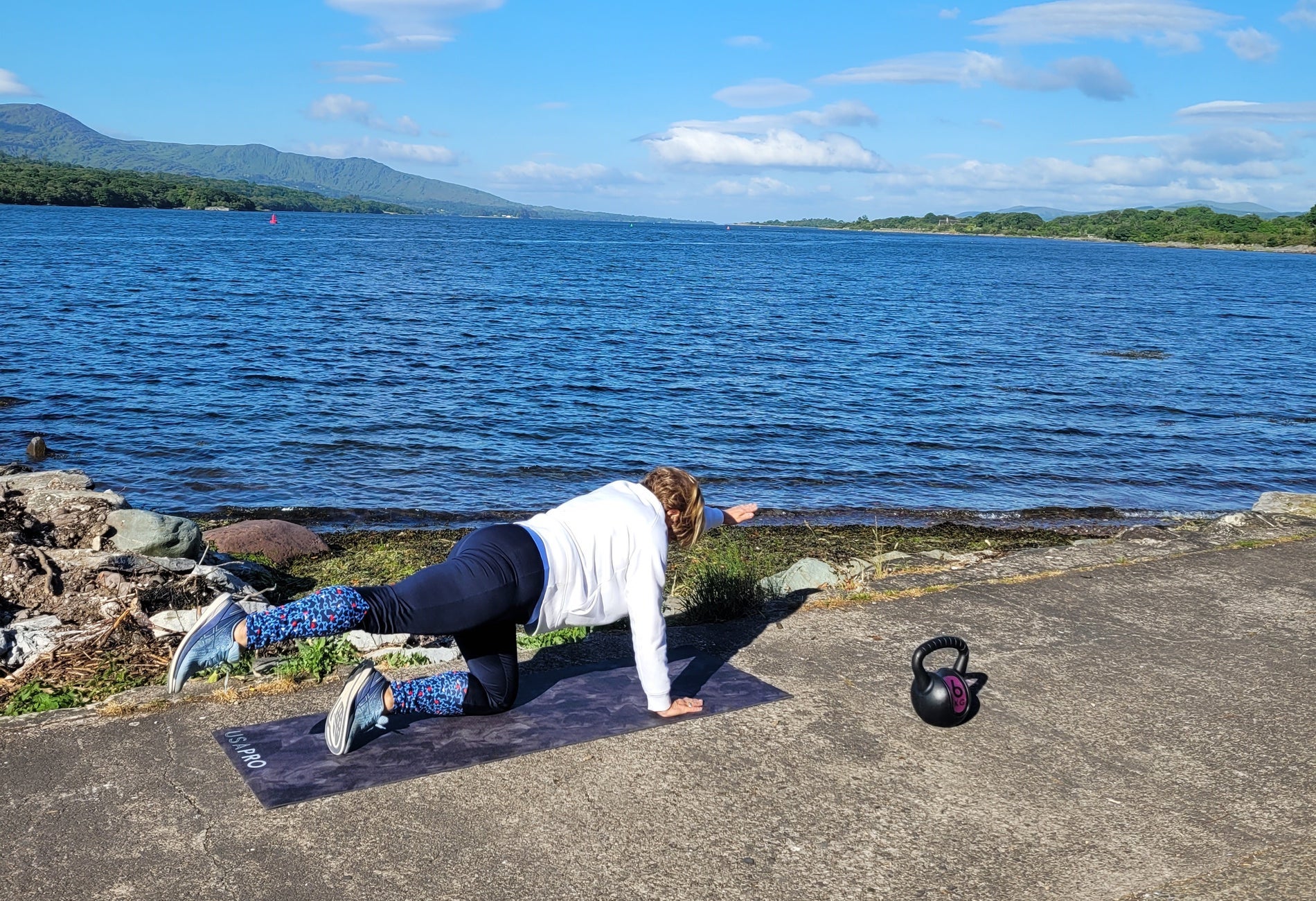 Person in a yoga pose on a pier next to the sea