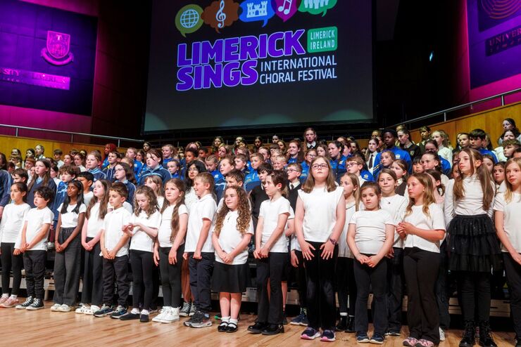 Large group of young children singing on a stage