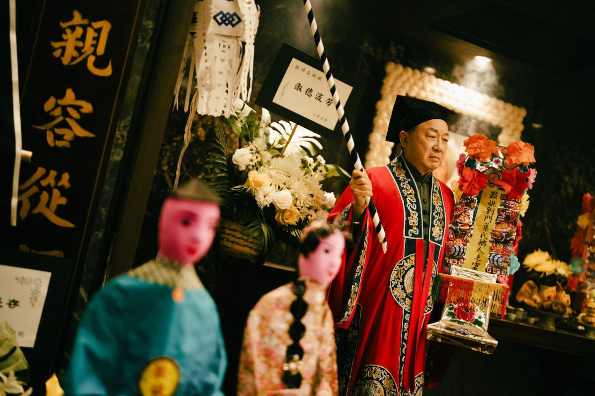 Film, The Last Dance, a man in ornate dress with flowers and blurred figures in the foreground.