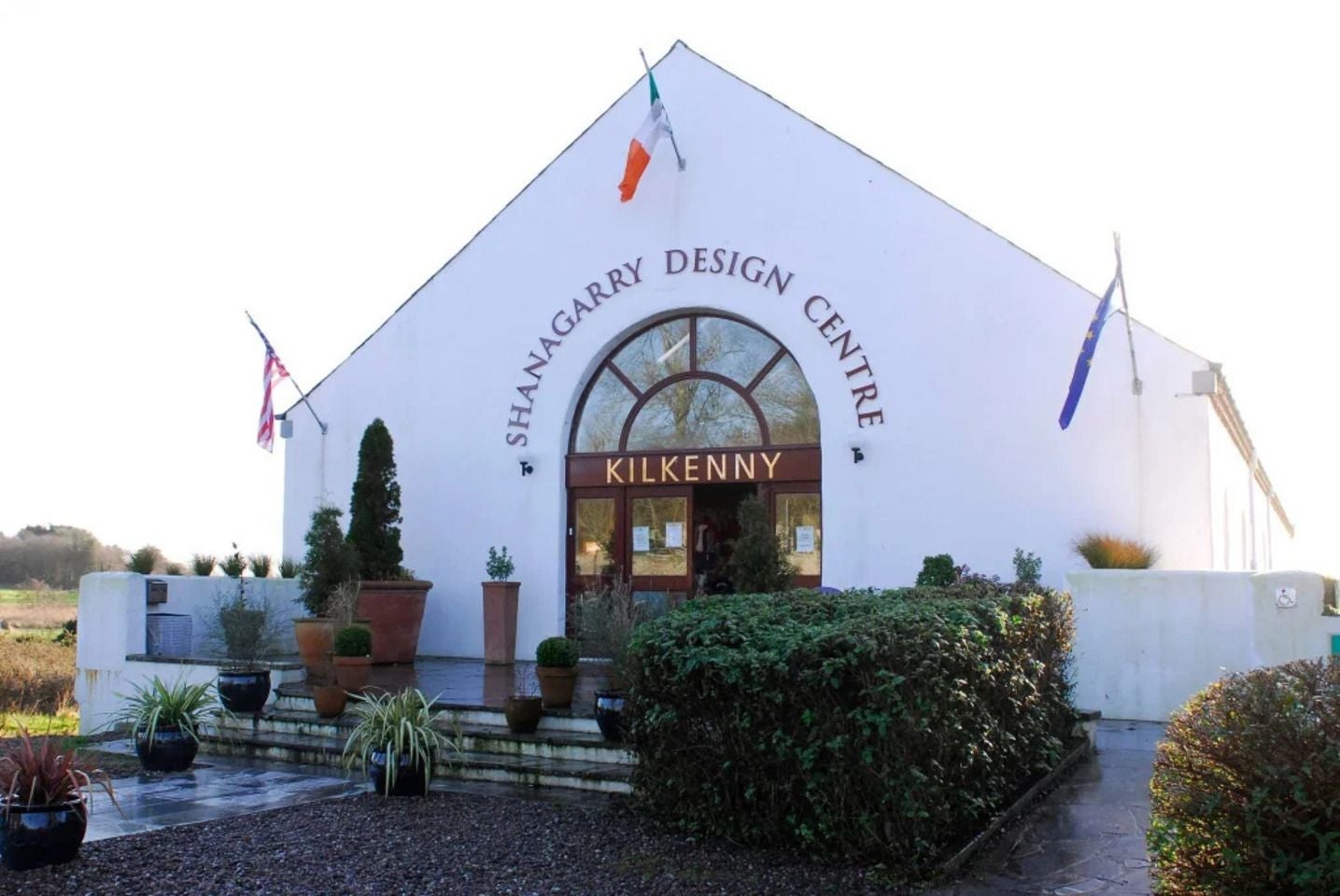White building with an arched entrance and landscaped gardens