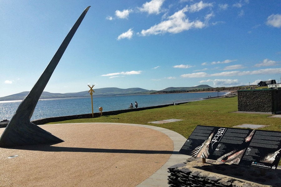 The Árthach Dána sculpture and sundial in Waterville with the bay in the background