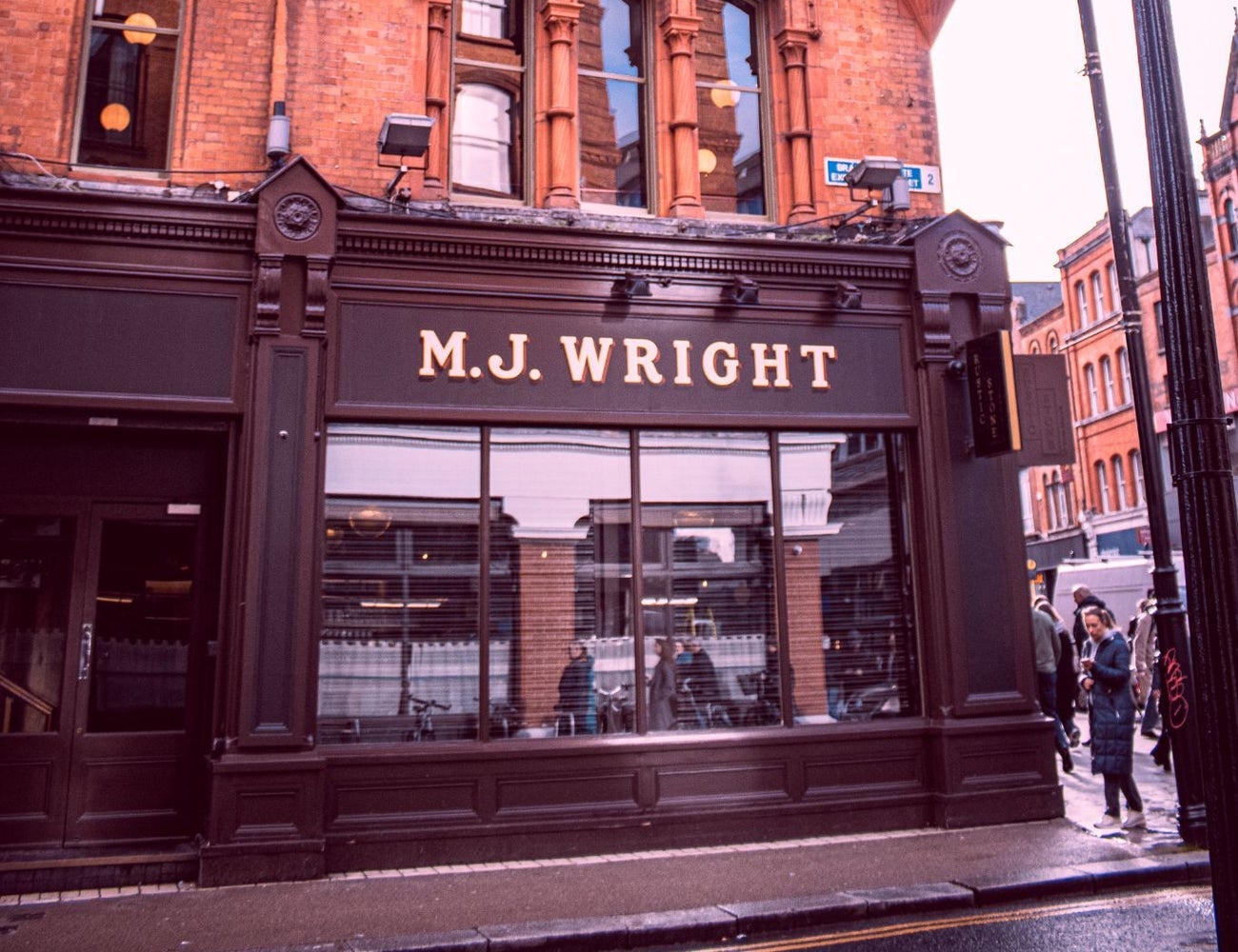 Exterior of a pub on a city street with the family name above the window