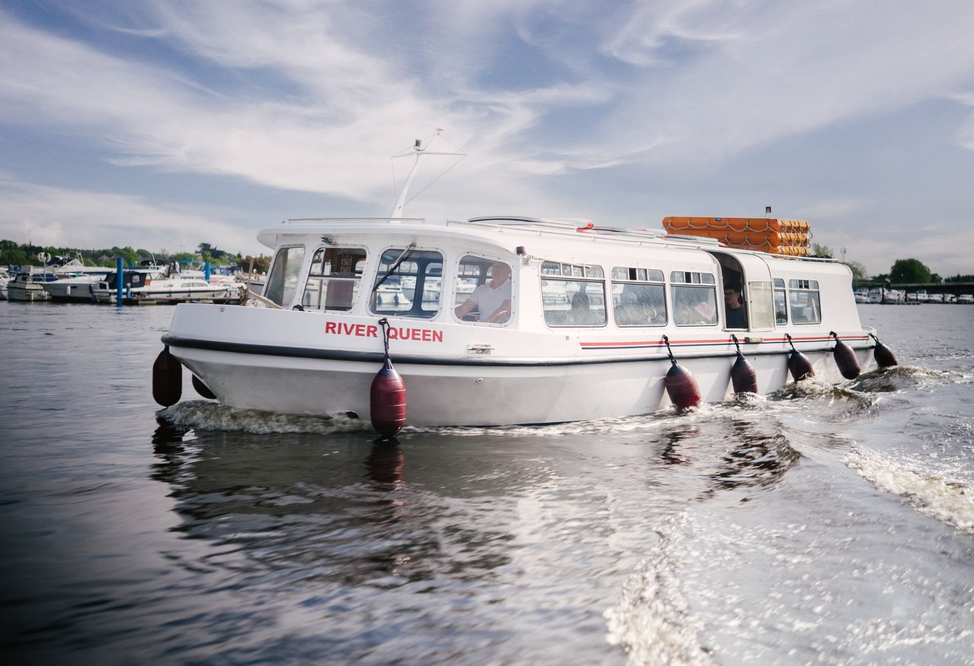 A white passenger boat named River Queen cruising on calm water