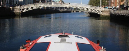 The boat cruising in the River Liffey approaching the Hapenny Bridge in Dublin City