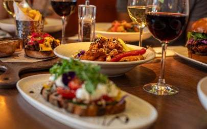 Different plates of food on a table with glasses of red and white wine