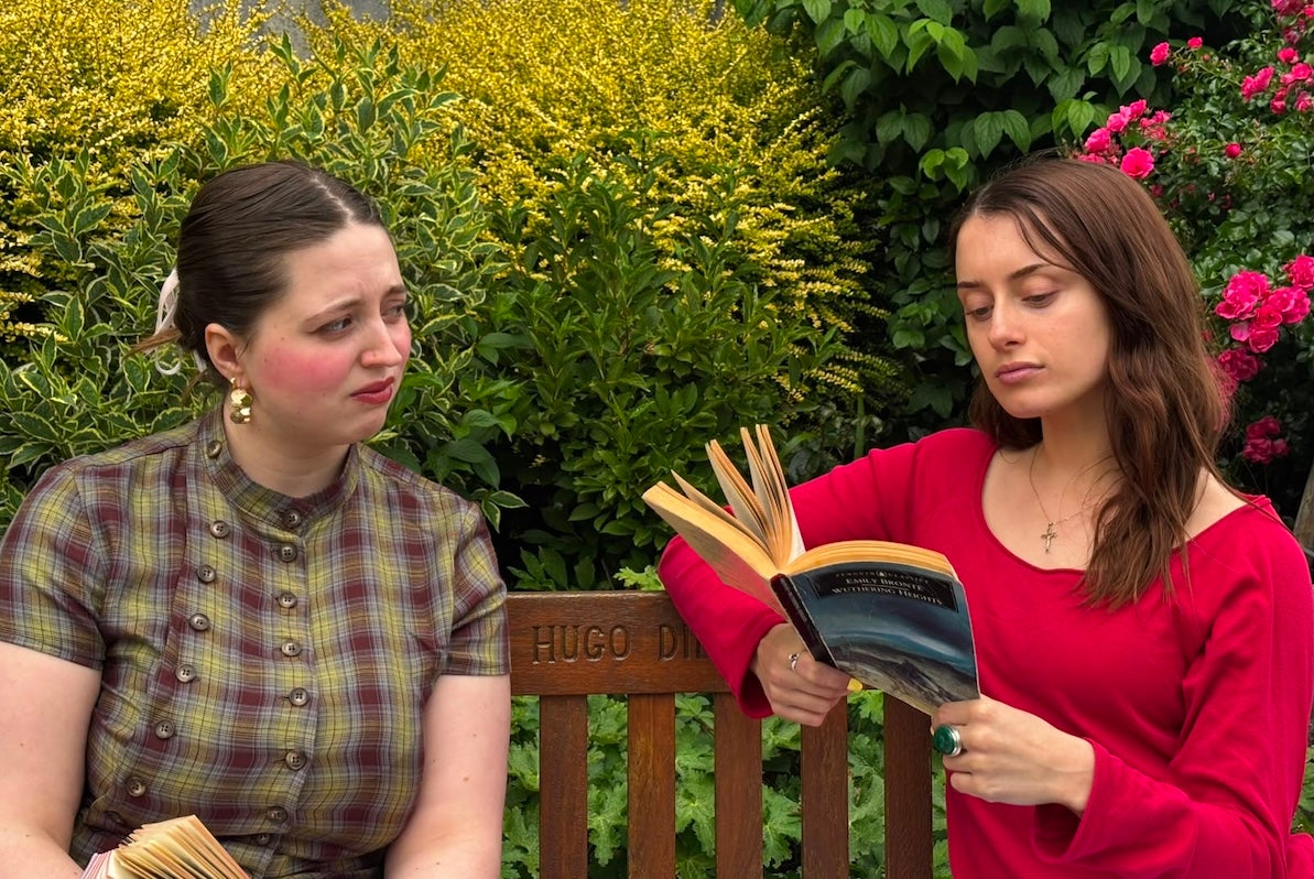 2 young women seated in a garden reading books