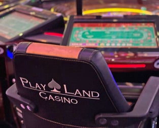 Playland Casino showing a comfortable chair in front of a gaming table
