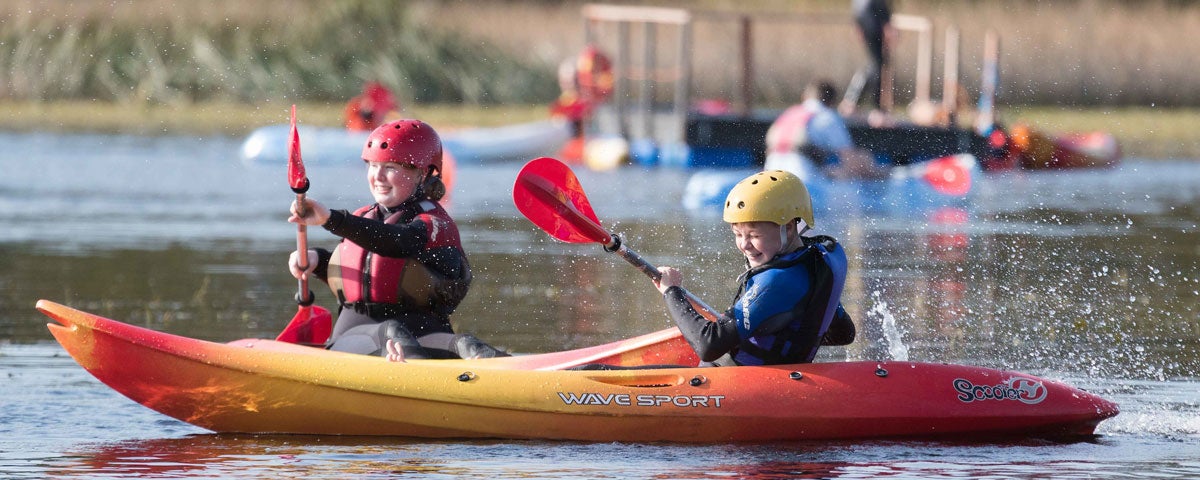 Two children on kayaks on a lake