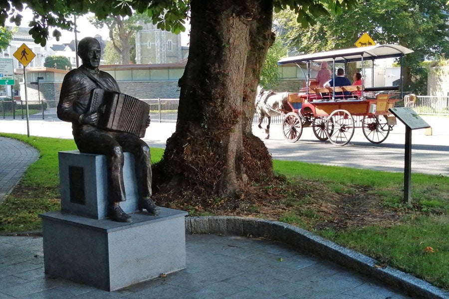 Bronze statue of local musician Johnny O'Leary captured in a seated position playing an accordion