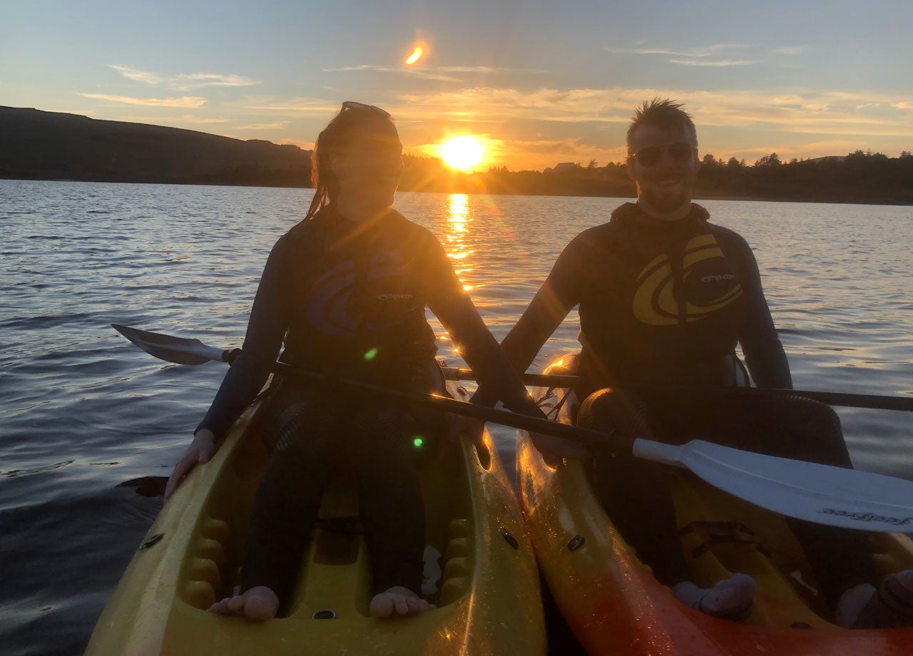Two people out on kayaks with the sunset in the background
