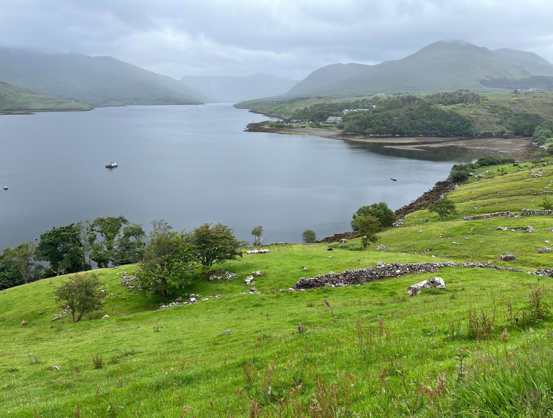 A lake by green fields with misty mountains in the background