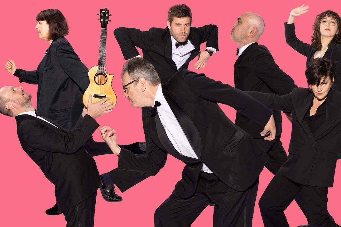 A group of people in black suits in various random poses against pink background.
