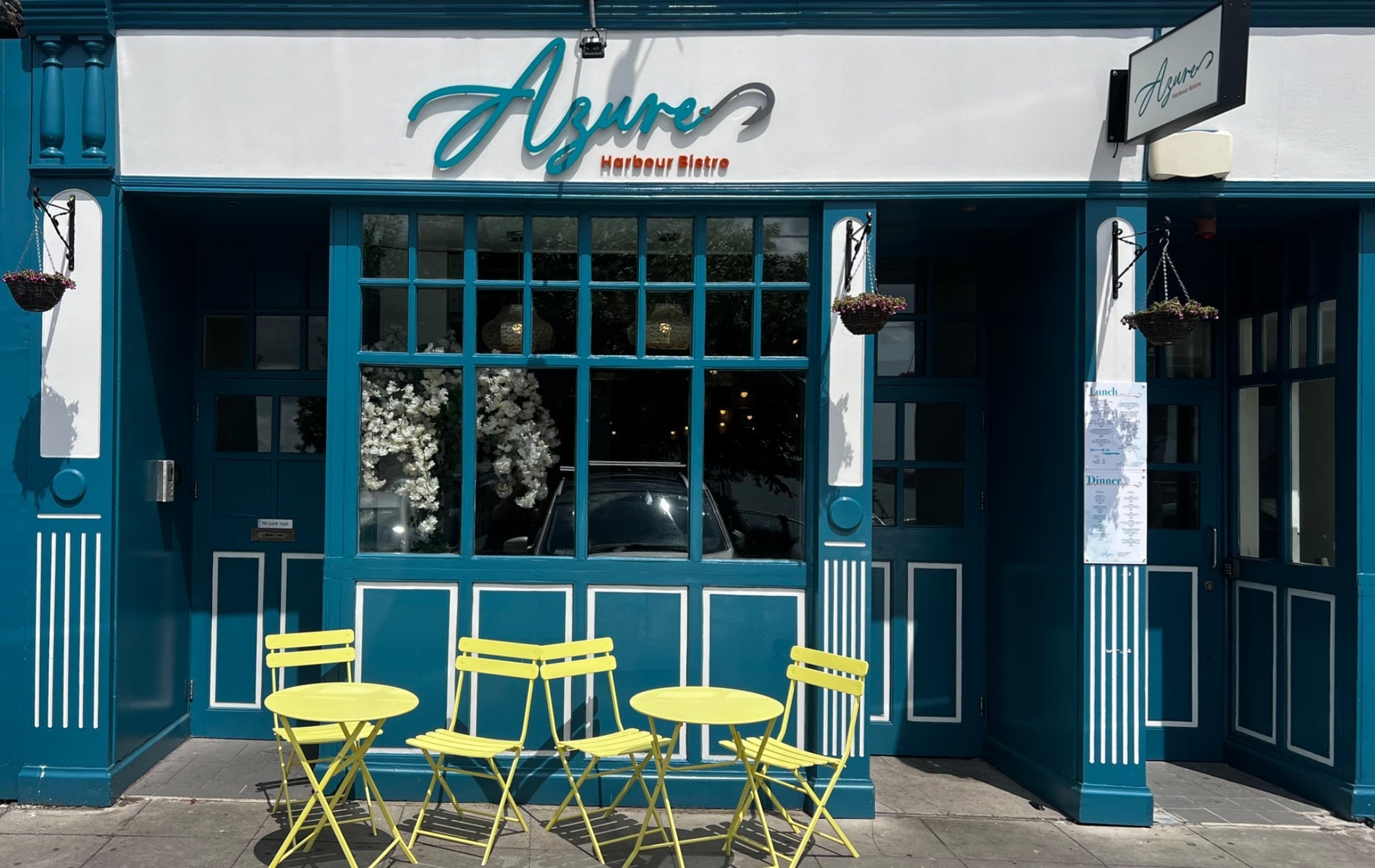 The exterior of a restaurant with green tables and chairs outside