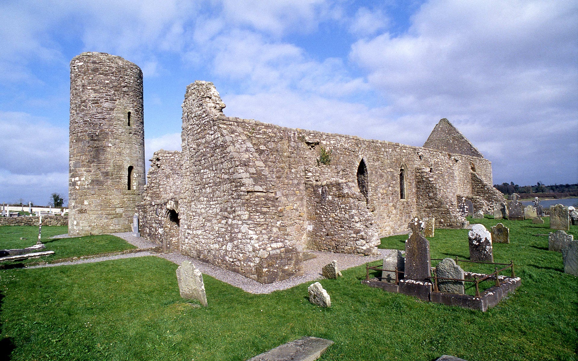 The ruins of an abbey with the remnants of a round tower beside it