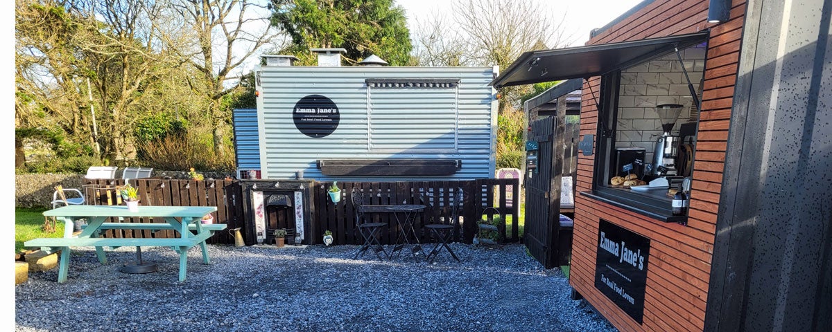 Exterior of a coffee hut and food truck with a picnic table outside