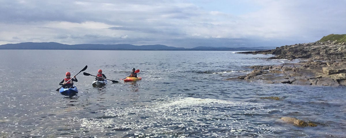 Lake and Coastal Kayak Adventures view of three kayakers on the coast