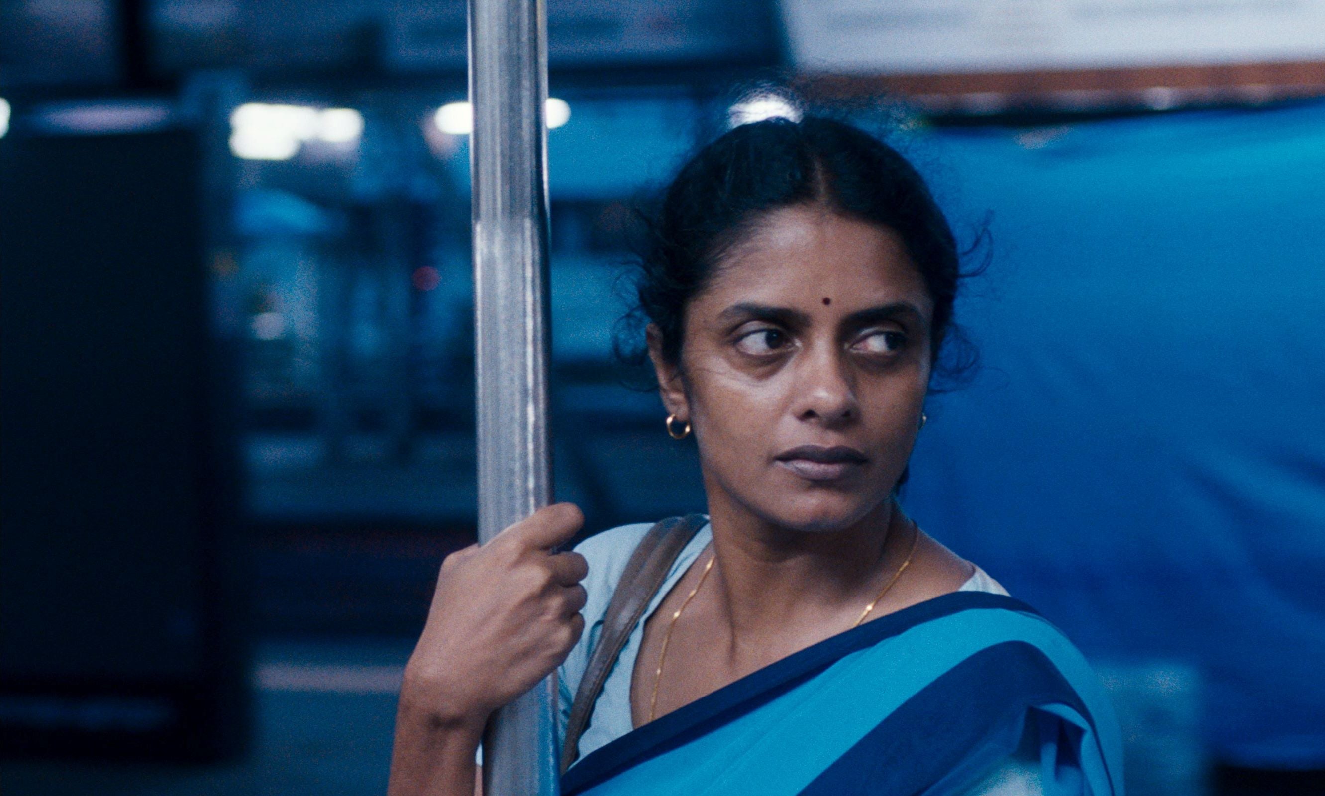 A worried Indian woman is on a train.