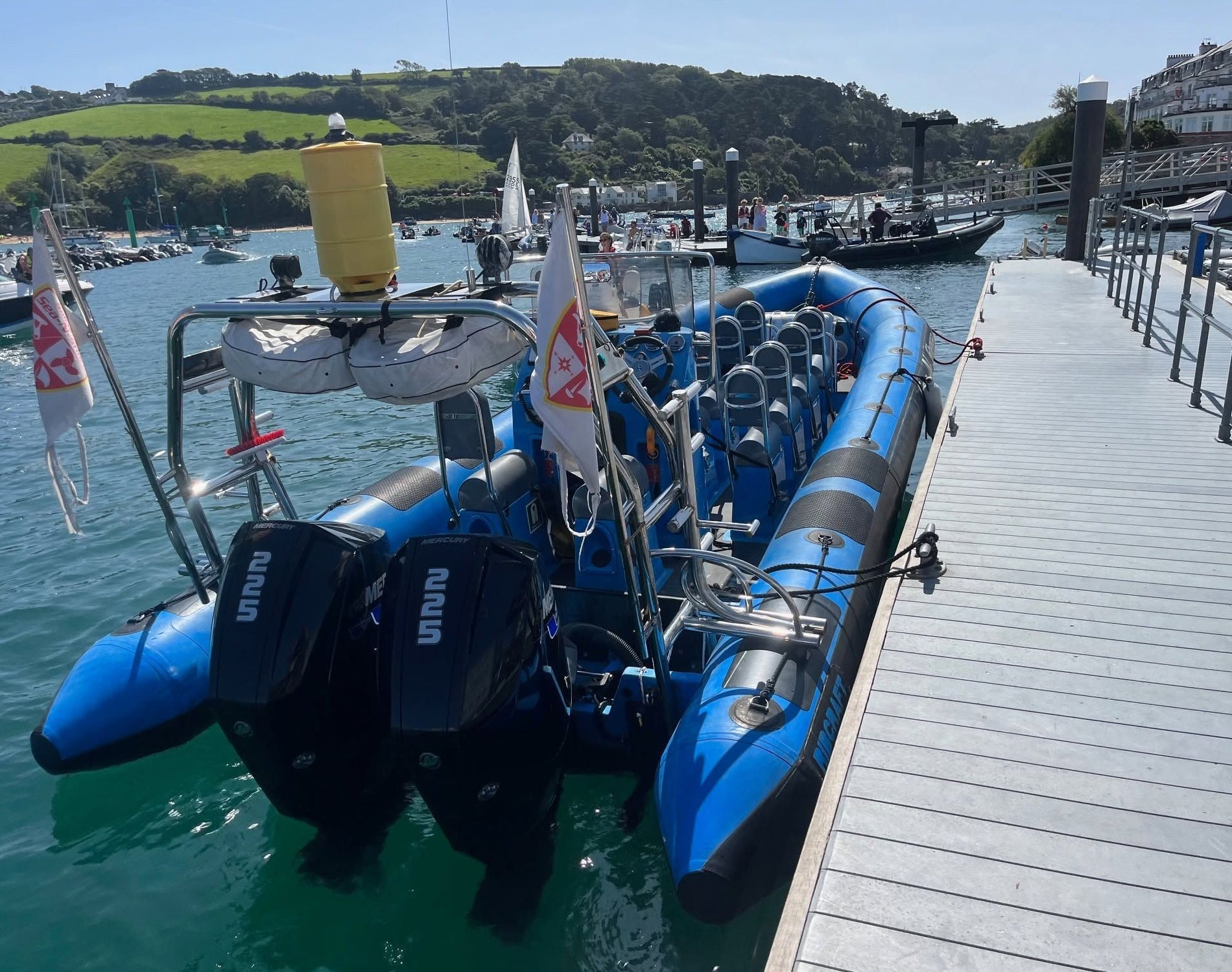 View of a blue rigid inflatable boat moored alongside a floating marina pontoon