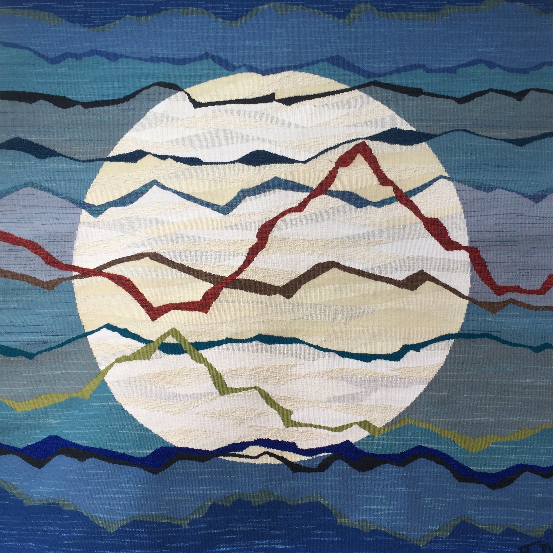 A tapestry showing what could be a full moon on a variegated blue background with colourful strips in foreground