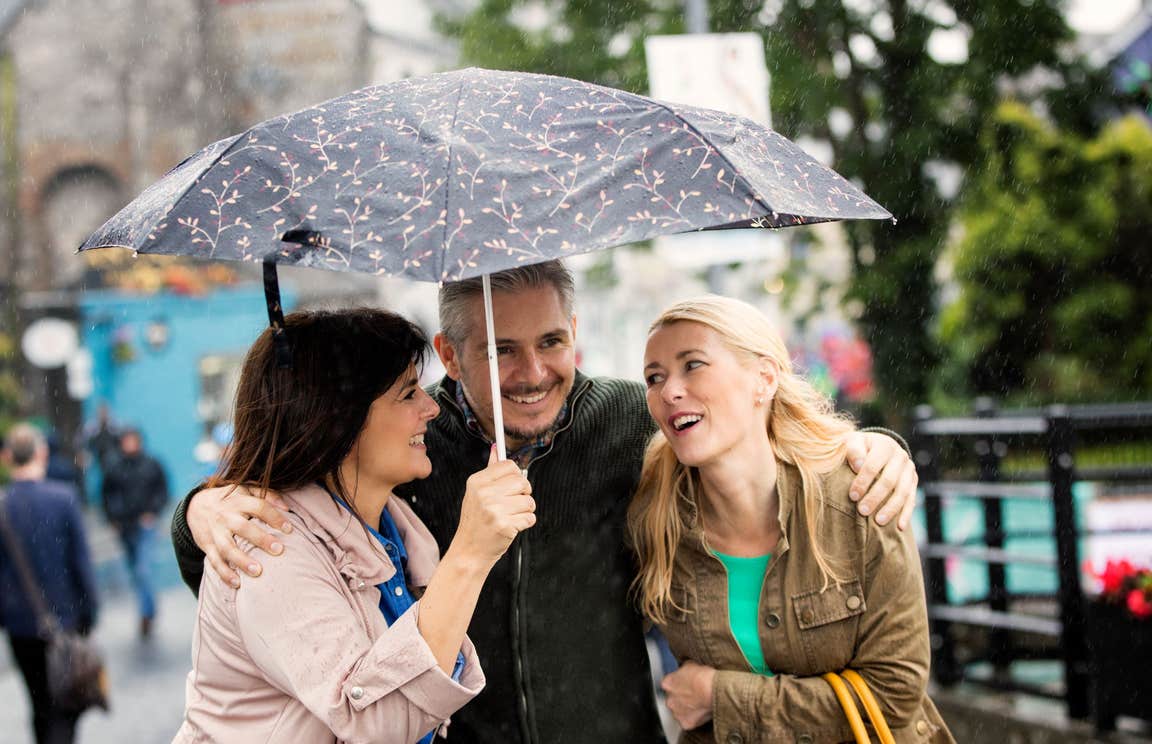 Three people standing under an umbrella in Ennis in County Clare