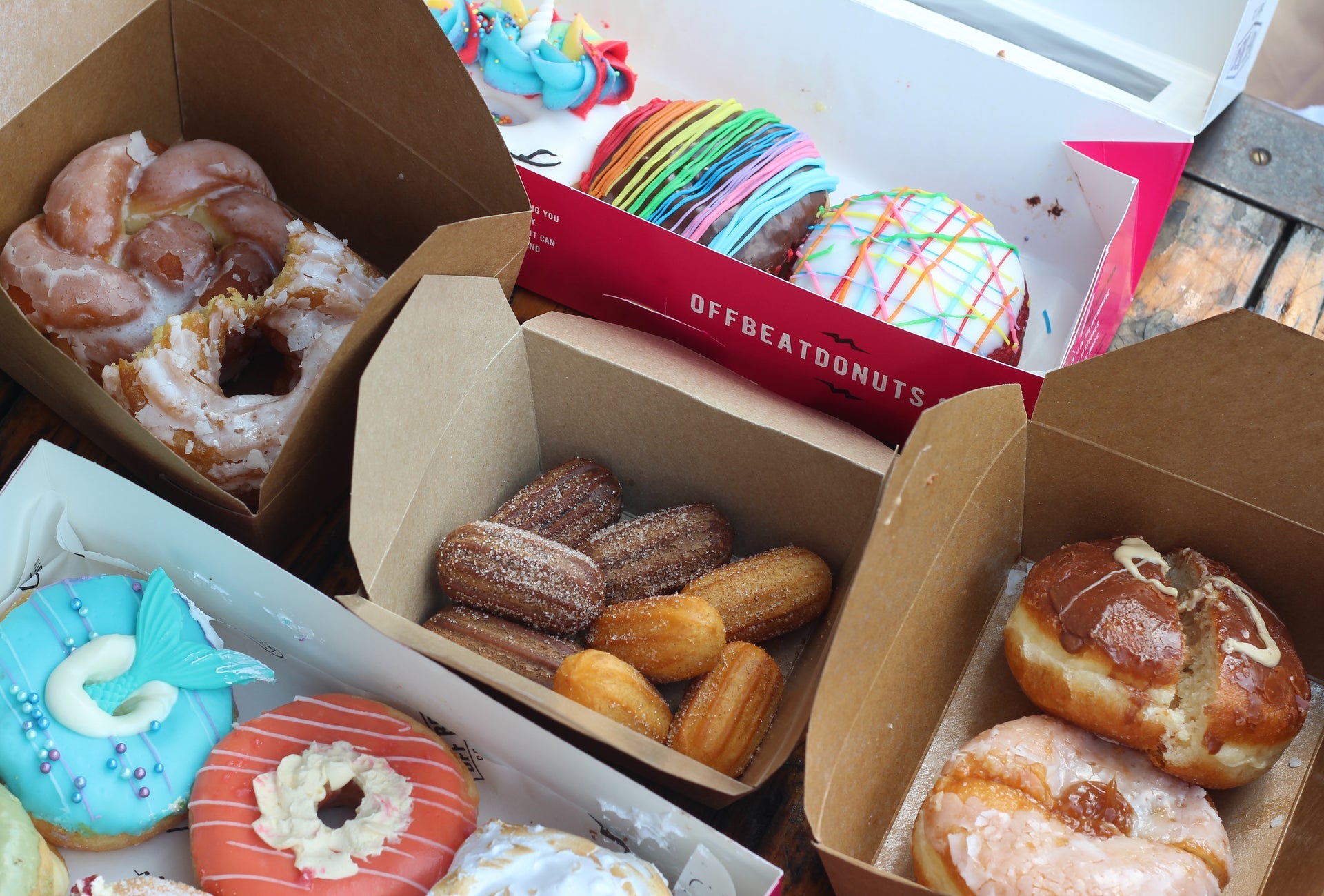 A selection of doughnuts of all shapes and sizes in four takeaway boxes