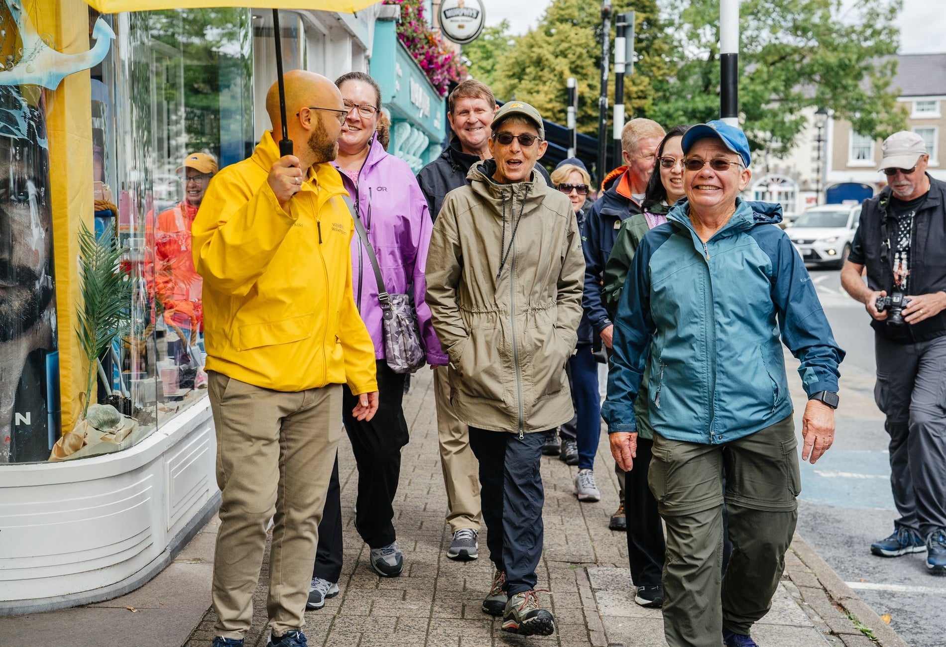Guide holding an umbrella leading a group of smiling people