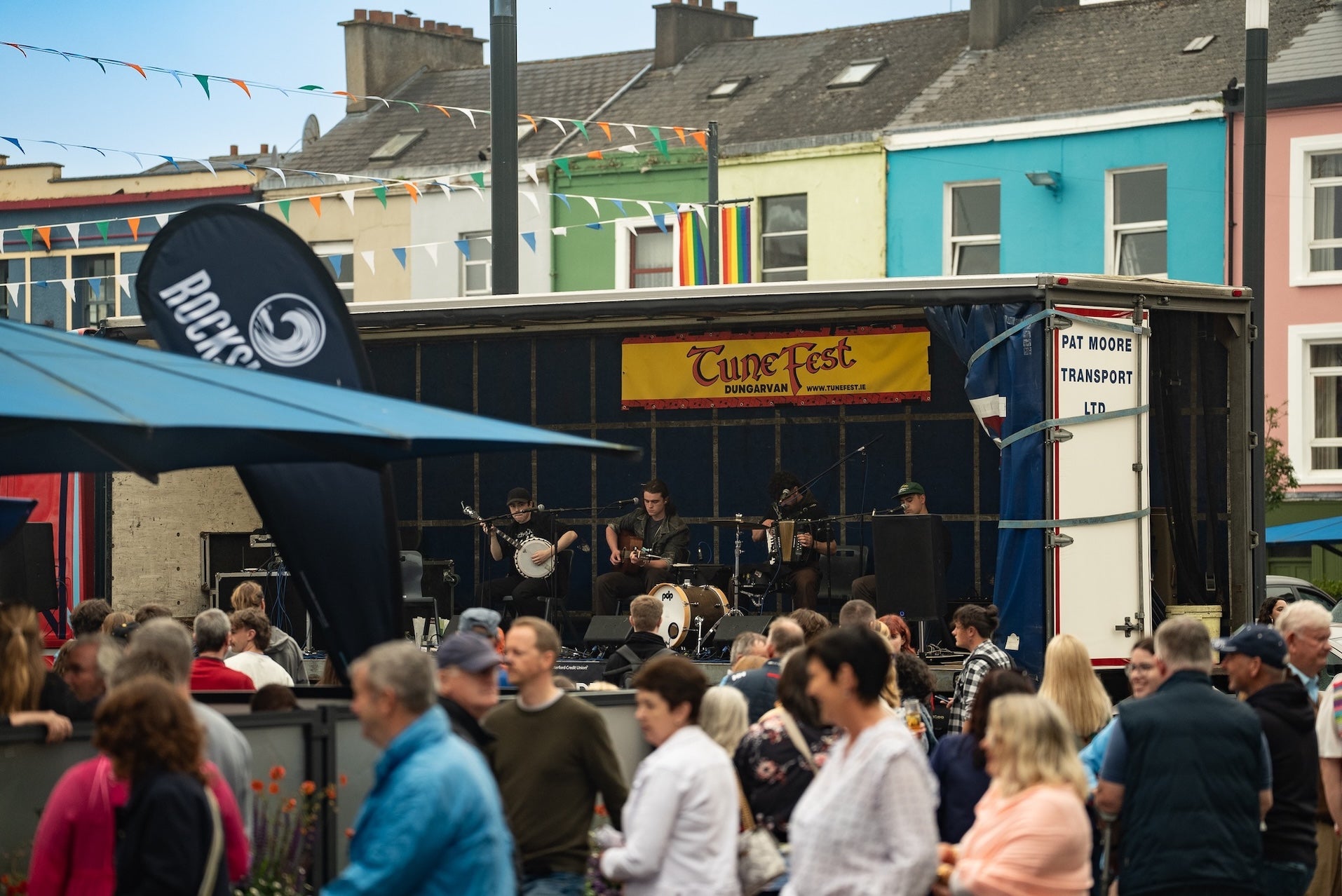 Dungarvan TuneFest 2026, people dancing outside in a town square with trad band playing on small stage.