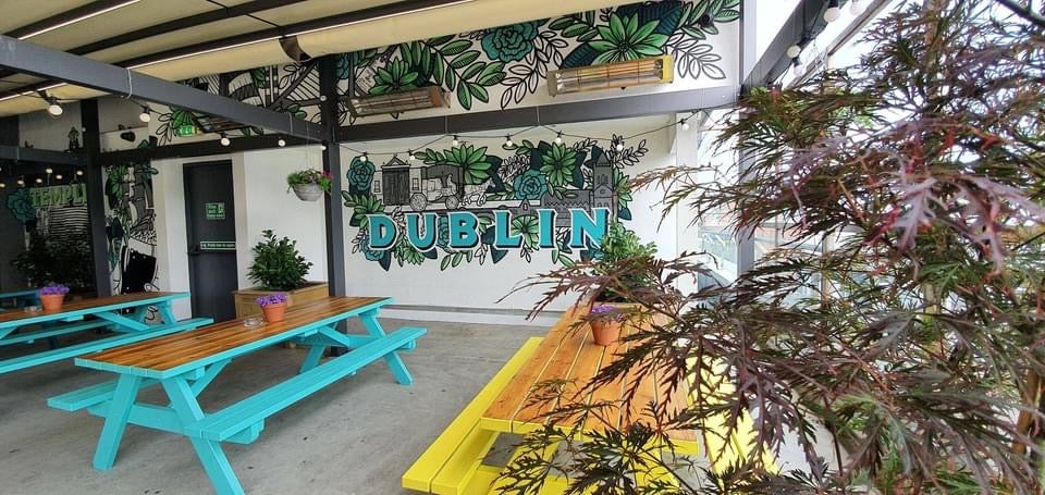 An outdoor seating area in a pub with picnic benches and lots of plants