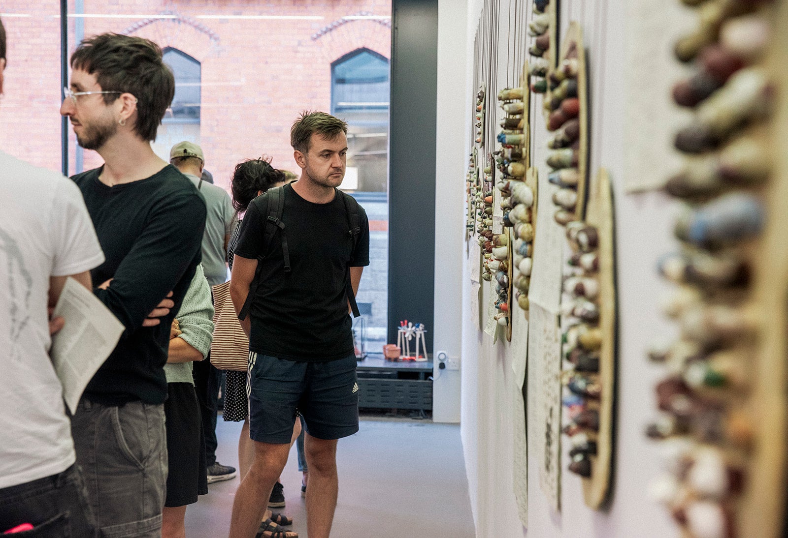 A man stands in a Gallery looking at art on the wall