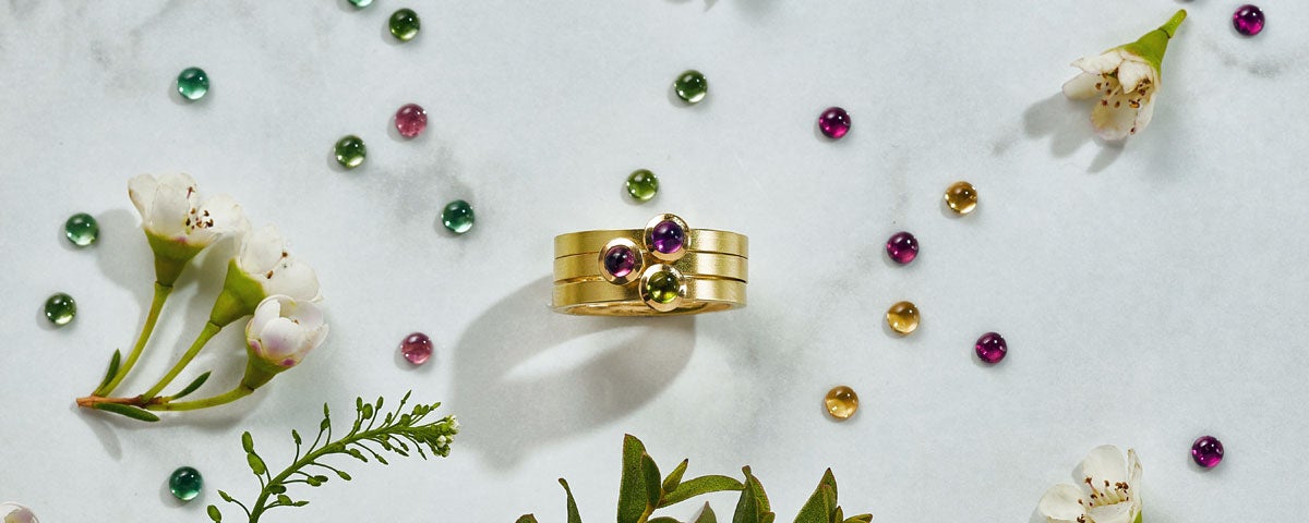 Image of gold ring with three stones and lots of coloured gems.