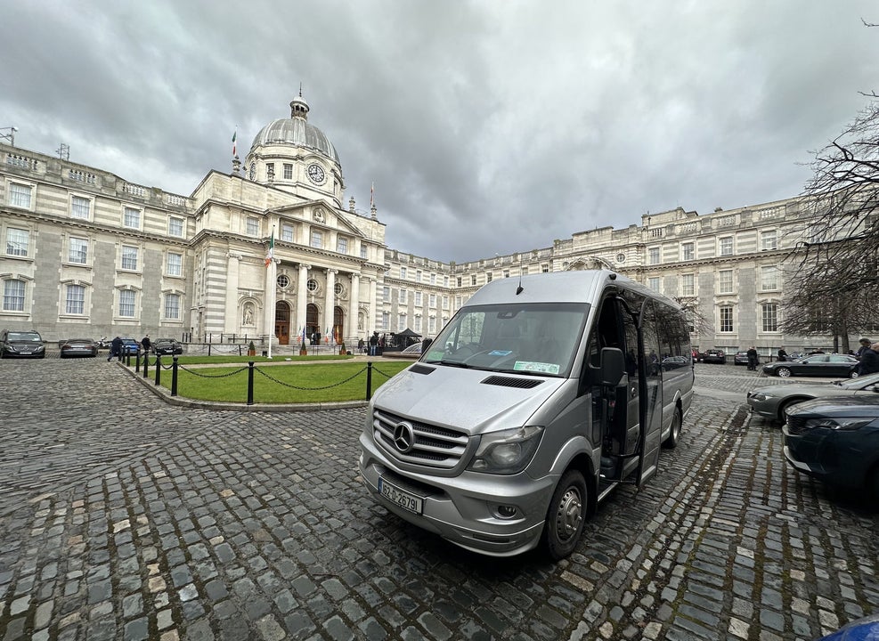 Silver minibus parked on a cobbled street in front of a large historic building