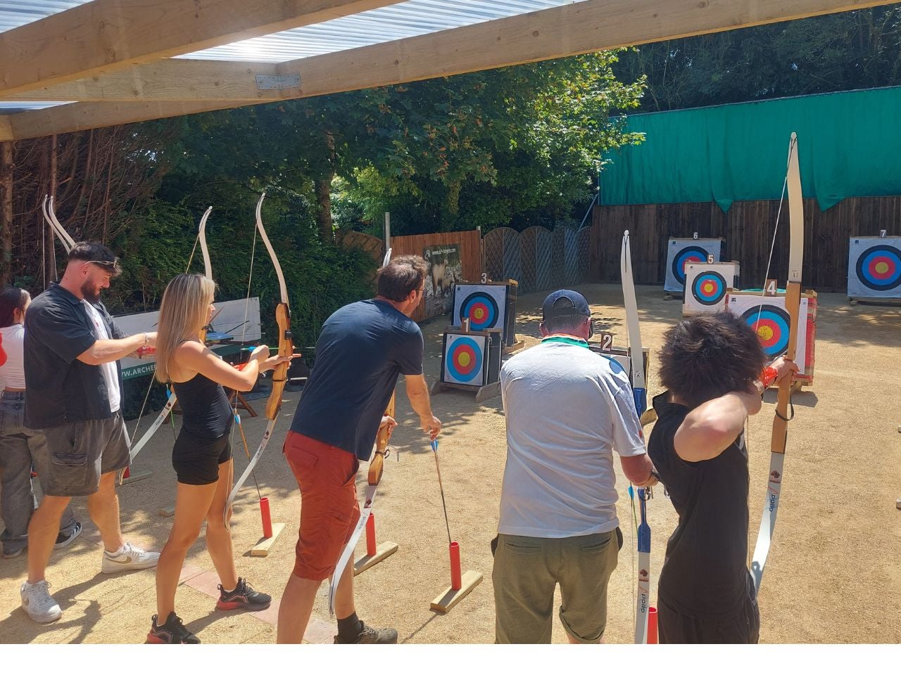 A group of people lined up in front of targets with bows in their hands