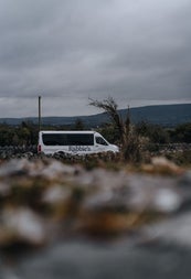 A small tour bus parked beside a country view