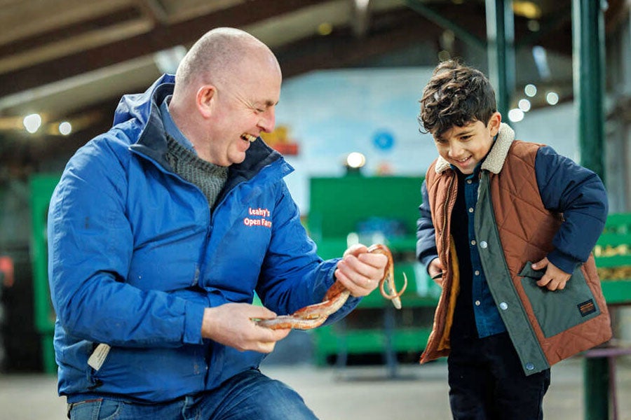 Leahy's Open Farm man laughing while showing a snake to a boy