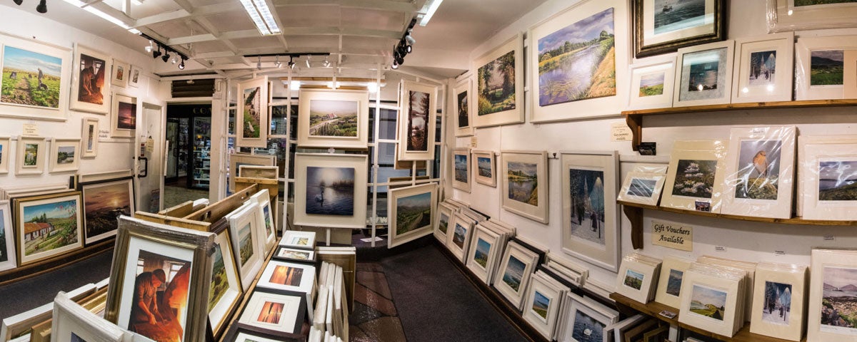 Interior of Jane Hilliard's gallery with framed paintings and prints lining the walls