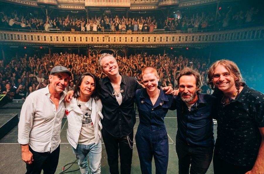 Jason Isbell & The 400 Unit, a line of people smiling on a stage with their back to a waving audience