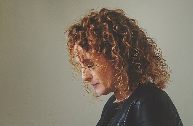 Side view of a woman with curly hair, looking downwards.