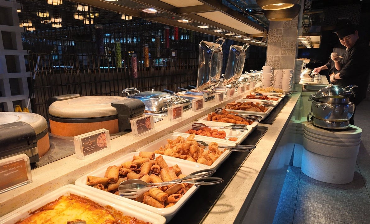 Various food dishes with tongs in white square ceramic serving bowls