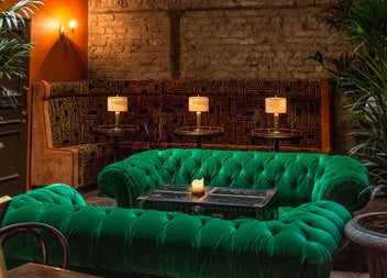 Green velvet couches in Idlewild with candlelit tables in the background