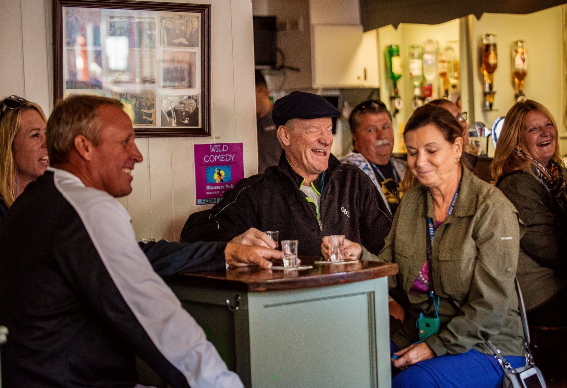 Group sitting in a pub at a tall table with empty shot glasses in front of them