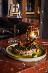 A glass of red wine on a red marble effect surface with a small plate dish