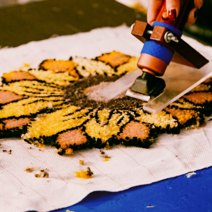 A guest shaving the details of a sunflower shaped rug.