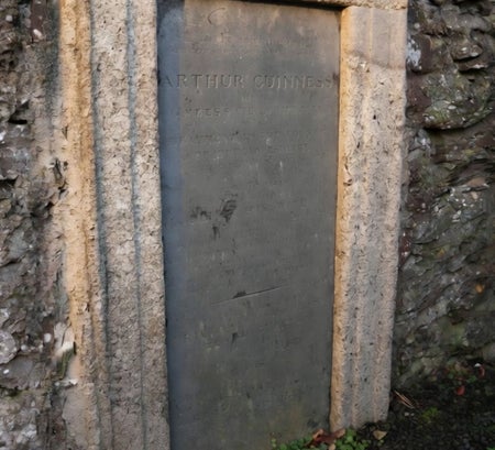Weathered stone grave marker set into an old stone wall