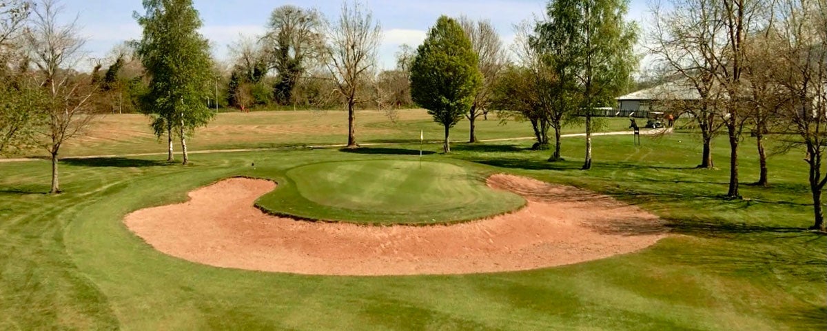 Semi circular shaped sand dune on the fairway of Slievenamon Golf Course with tress in background
