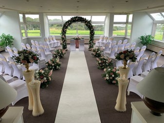 Function room set up for a wedding with chairs and flowers