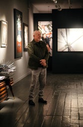The artist poses for a photograph in front of his work inside a gallery