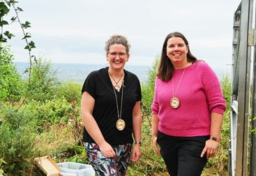 Two ladies posing with smiles with hills in the background